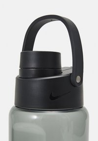 Nike waterfles met een grijze plastic behuizing en een zwarte plastic dop. De dop heeft een zwarte lus handvat en logo. Gladde textuur, slank ontwerp.