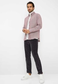 Rood-witte geblokte overhemden met een borstzakje aan de linkerkant, gecombineerd met donkere corduroy broeken en witte sneakers. Gladde texturen, casual ontwerp.