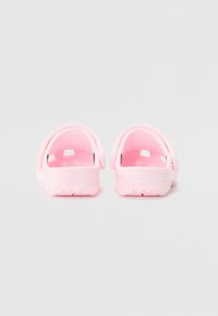 Pink clogs with a smooth plastic finish, open back, and cut-out ventilation holes. Textured sole for grip. No visible hardware or accents.