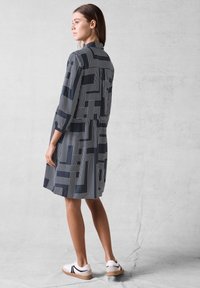 Abito navy con motivi geometrici bianchi, colletto abbottonato, maniche a tre quarti e vestibilità comoda, abbinato a sneaker bianche.
