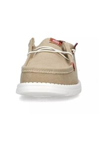 Sneaker in canvas beige con suola in gomma bianca, caratterizzata da una costruzione leggera, dettagli cuciti e un'etichetta rossa sul lato.