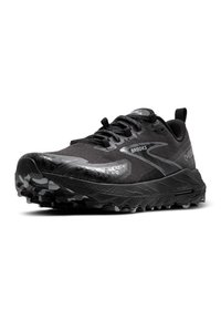 Zapatilla de trail running negra con parte superior de tejido texturizado, acentos reflectantes y suela robusta con tacos profundos para tracción. Se puede ver la marca Brooks.