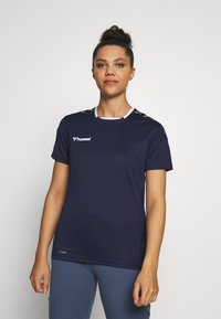 Marineblå atletisk t-shirt lavet af åndbart stof, med rund hals, korte ærmer og kontrasterende skulderdetaljer med logo.