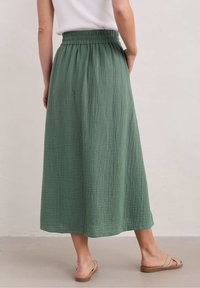 Gonna verde di lunghezza midi realizzata in cotone testurizzato, con vita elastica. Design semplice, abbinata a sandali flat.