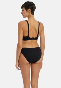 Sort bikini-sæt med struktureret stof. Toppen har tynde stropper og en spænde-lukning. Bunden har et højt talje-design.