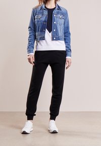 Světlá modrá crop džínová bunda, vrstvený top v námořnické modré a bílé barvě, černé teplákové kalhoty a bílé tenisky, všechny s elastickými manžetami a hladkými texturami.