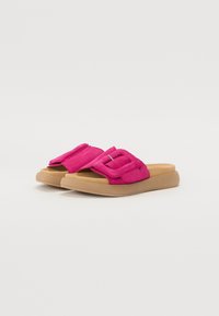 Rosa mockaläder slide-sandaler med en bred rem och detaljerad fyrkantig spänne samt en tanfärgad gummisula. Mjuk textur och avslappnad design.