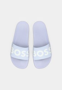 Ανοιχτό μωβ σαγιονάρες με υφασμένο πέλμα και ευρύ λουράκι που φέρει τη λέξη "BOSS" σε λευκό. Απλός, μινιμαλιστικός σχεδιασμός.