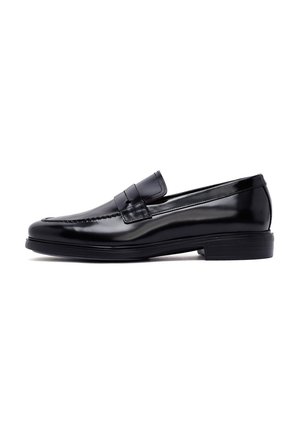 Mocassins en cuir noir avec une texture lisse, un bout rond, des coutures décoratives et une semelle en caoutchouc à profil bas.