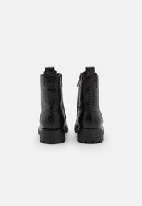 Bottines noires avec un empiècement en cuir texturé à motif crocodile, talon bloc bas et fermeture éclair sur le côté. Semelle en caoutchouc épaisse.