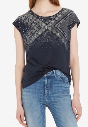 Donna che indossa una maglietta blu scuro a maniche corte con motivo infilata in jeans blu a lavaggio medio, mostrata dalle spalle ai fianchi.