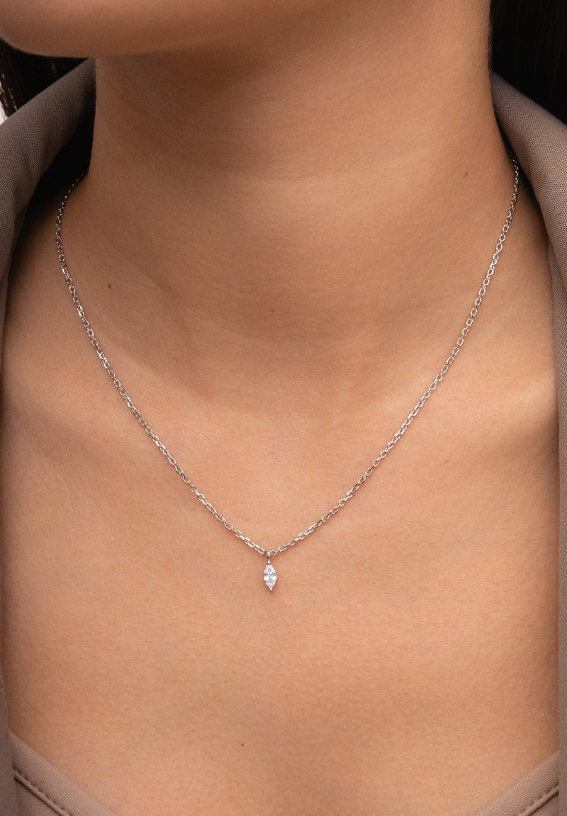 Collier délicat en chaîne d'argent avec un petit pendentif en pierre précieuse claire taillée en marquise reposant à la base du cou.