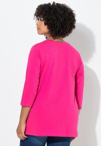 Fuchsia Langarmshirt mit lockerer Passform, rundem Halsausschnitt und nahtlosem Rückendesign. Weiche Textur und mittellange Länge.