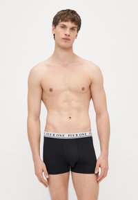 Czarne bokserki z miękkim elastycznym pasem w talii z białym napisem. Materiał wydaje się gładki i elastyczny, zaprojektowany z myślą o komforcie.