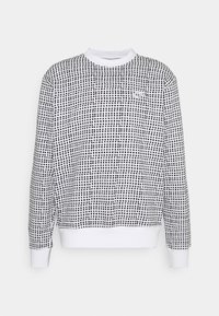 Sudadera en blanco y negro con un patrón de cuadrícula, cuello redondo y mangas largas con puños y dobladillo acanalados. Fabricada con una tela suave y ligera.