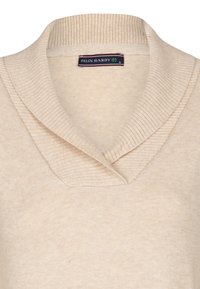 Maglione beige lavorato a maglia con colletto a scialle a coste e una texture morbida. L'etichetta all'interno del colletto riporta "FELIX HARDY".