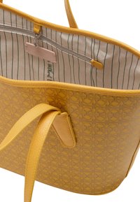 Borsa tote gialla realizzata in materiale testurizzato, con un esterno a motivo e una foderatura in tessuto a righe, dotata di una tasca con zip all'interno.