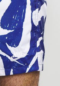 Blå och vita mönstrade shorts med en abstrakt design, med en vit Nike-logotyp på ena sidan. Tillverkade av lättviktig tyg.
