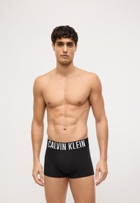 Czarne bawełniane bokserki z białym logo "CALVIN KLEIN" na pasie, o dopasowanym kroju i gładkiej fakturze.