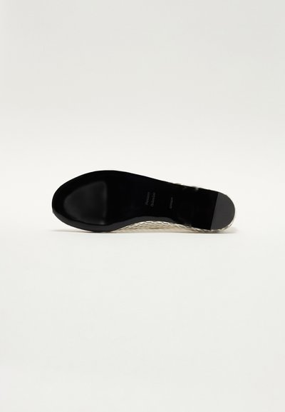 Sort skindsål med en glat tekstur, der har et vævet mønster i siderne og en afrundet tå. Designet fremhæver holdbarhed og greb.