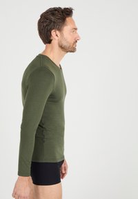 Langarm, slim-fit t-shirt van donkergroen katoen met een ronde hals, featuring naadloze schouders en een zachte textuur.
