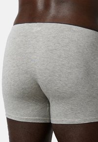 Boxer in cotone grigio con design aderente. Tessuto morbido con un cinturino nero, caratterizzato da dettagli di cucitura sottili.