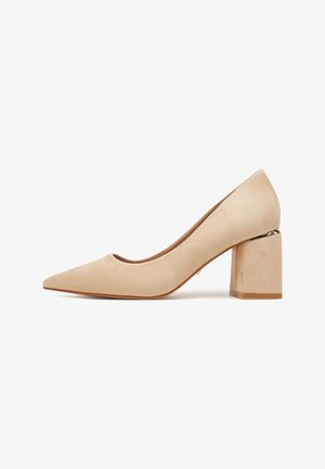Beige suede women's pump with pointed toe and block heel featuring a metallic accent near the sole.