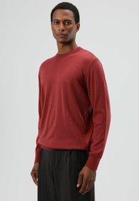 Rode trui met lange mouwen gemaakt van zachte stof, met een ronde hals en geribbelde manchetten, gecombineerd met donkere broek met krijtstreepjes.