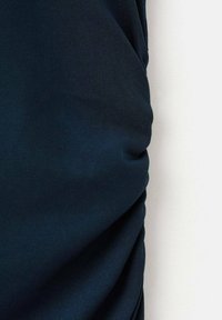 Tela de color azul oscuro con una textura suave, que presenta detalles recogidos y un diseño elástico, centrado principalmente en su apariencia drapeada.