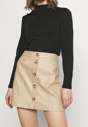 Beige Leder-Minirock mit geradem Schnitt, ausgestattet mit einer vorderen Knopfleiste und subtilen gestickten Details. Schwarzes langärmliges Oberteil mit Schimmer.