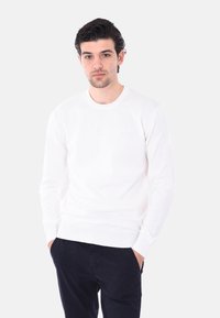 Maglione bianco a maglia con scollatura rotonda e maniche lunghe, abbinato a pantaloni scuri. Design semplice e texture liscia, adatto per un abbigliamento casual.