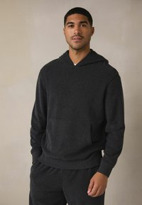 Kulfarvet hættetrøje lavet af blødt stof, med en frontlomme, snoretræk i hætten og ribbet manchet og bund. Parret med matchende bukser.