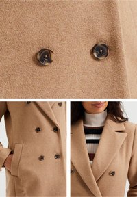 Double-breasted beige coat made of soft wool blend, featuring large dark buttons, and a classic lapel design. Includes side pockets.