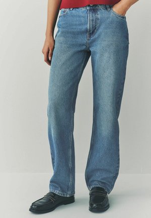 Lichtblauwe straight-leg jeans van denim. Heeft een hoge taille, een klassieke vijf-pocketontwerp en subtiele vervaging. Gepaald met zwarte instappers.