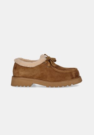 Zapato de ante marrón con suela gruesa, forro interior de piel y cordones delanteros, mostrado de lado sobre un fondo claro y liso.