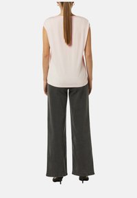 Jasnoróżowa bluzka z krótkim rękawem połączona z szerokimi, ciemnoszarymi spodniami. Bluzka ma gładką teksturę, podczas gdy spodnie mają wygląd przypominający dżins.