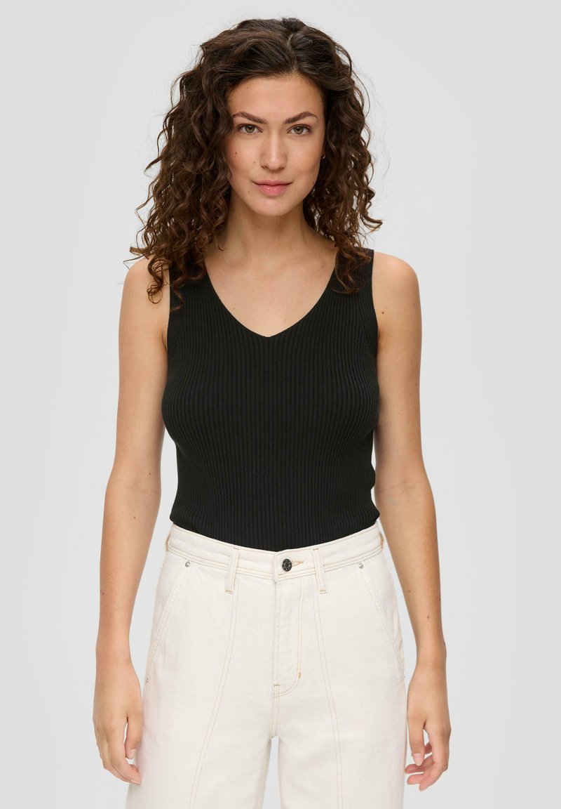 Czarny prążkowany top na ramiączkach z dekoltem w serek, w połączeniu z białymi spodniami na wysoki stan z zapięciem na guzik i kieszeniami z przodu.