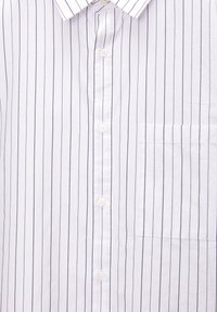 Chemise blanche à boutons avec de fines rayures verticales foncées et une poche poitrine du côté droit.