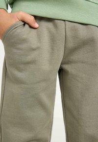 Joggebukser i bomuldsblanding i olivengrøn med blød tekstur, med sidelommer og afslappet pasform. Søm detaljer forbedrer designet.