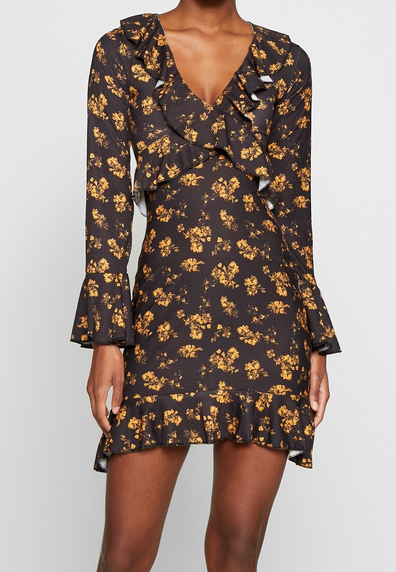 Robe noire à fleurs avec des manches longues, un col froncé et des poignets volantés, ornée de fleurs jaunes, silhouette ajustée et un ourlet à volants évasé.