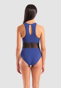 Costume da bagno intero blu con schiena alta, fascia nera a metà corpo e dettaglio a fessura sul collo. Tessuto liscio e elasticizzato.