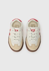 Beige og elfenben sneakers med røde aksenter, med en kombinasjon av lær og semsket lær, rund tå, snøring, og teksturerte såler.