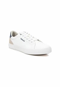 Zapatillas deportivas blancas con un acabado de piel suave, acentos en crema y azul marino, cordones planos y una suela de goma más gruesa. Logo exhibido en el lateral.