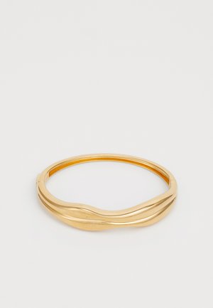 Guldtonet bangle armbånd med et glat, bølget design. Har en poleret overflade og en cirkulær form, der giver et moderne, minimalistisk udseende.