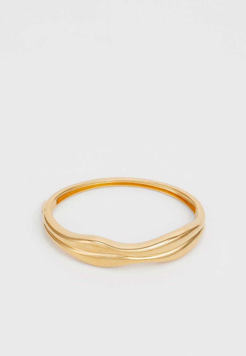 Bracelet jonc en ton or avec un design lisse et ondulé. Doté d'une finition polie et d'une forme circulaire, offrant un look moderne et minimaliste.