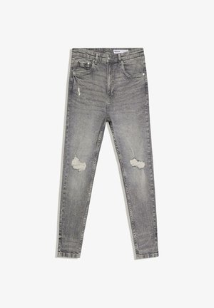 Szürke, karcsúsított szabású, kopott farmernadrág két szakadt folttal a combokon, első zsebekkel és övbújtatókkal, fehér háttéren laposan elhelyezve.