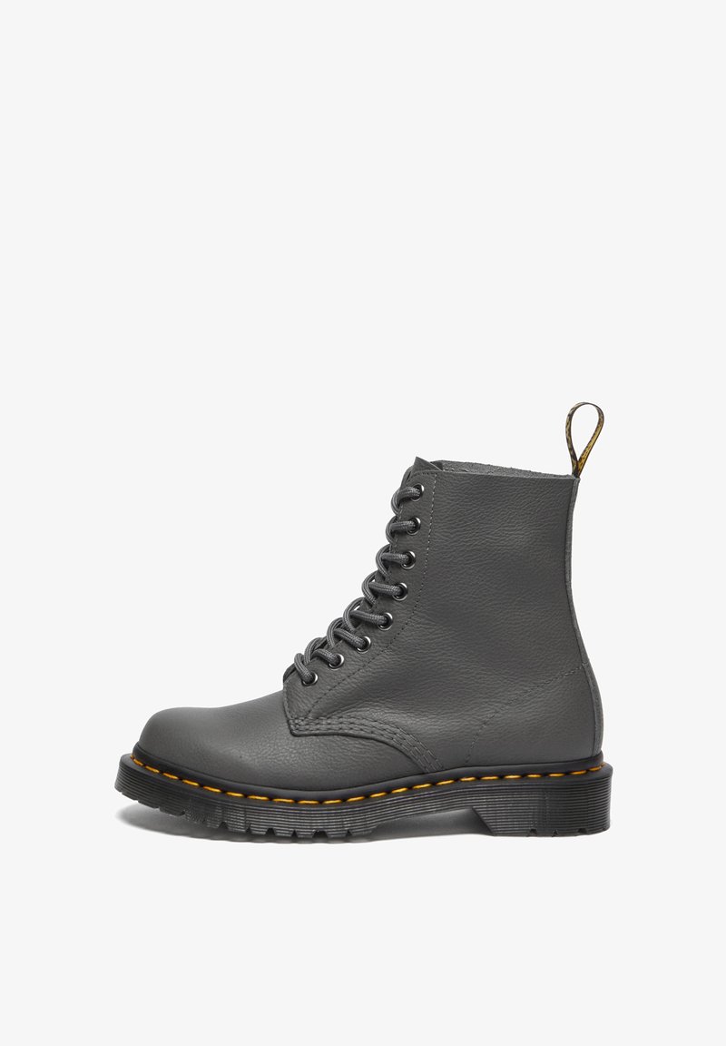 Bota de cuero gris con cordones, punta redonda, costuras amarillas, superficie texturizada, asa en la parte trasera y suela de goma negra gruesa.