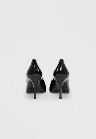 Chaussures à talons hauts en cuir verni noir avec un bout pointu, présentant une texture lisse et brillante ainsi que de fins talons aiguille.