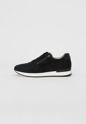 Black suede sneaker with a textured finish, featuring a white rubber sole, lace closure, and a side zipper detail.