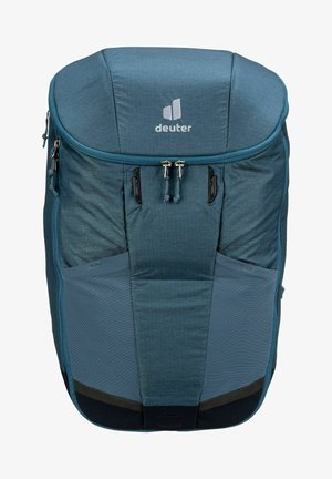 Sac à dos en tissu bleu avec un dessus arrondi, fermeture éclair, poches avant et logo. Matériau texturé avec des accents plus clairs et un fond noir.